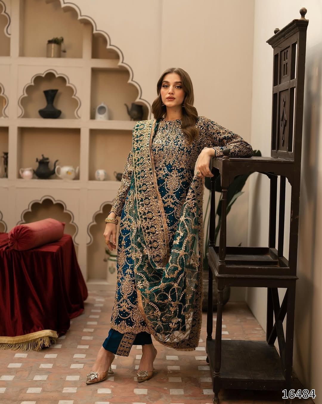 Woman in traditional attire standing in a decorative interior setting